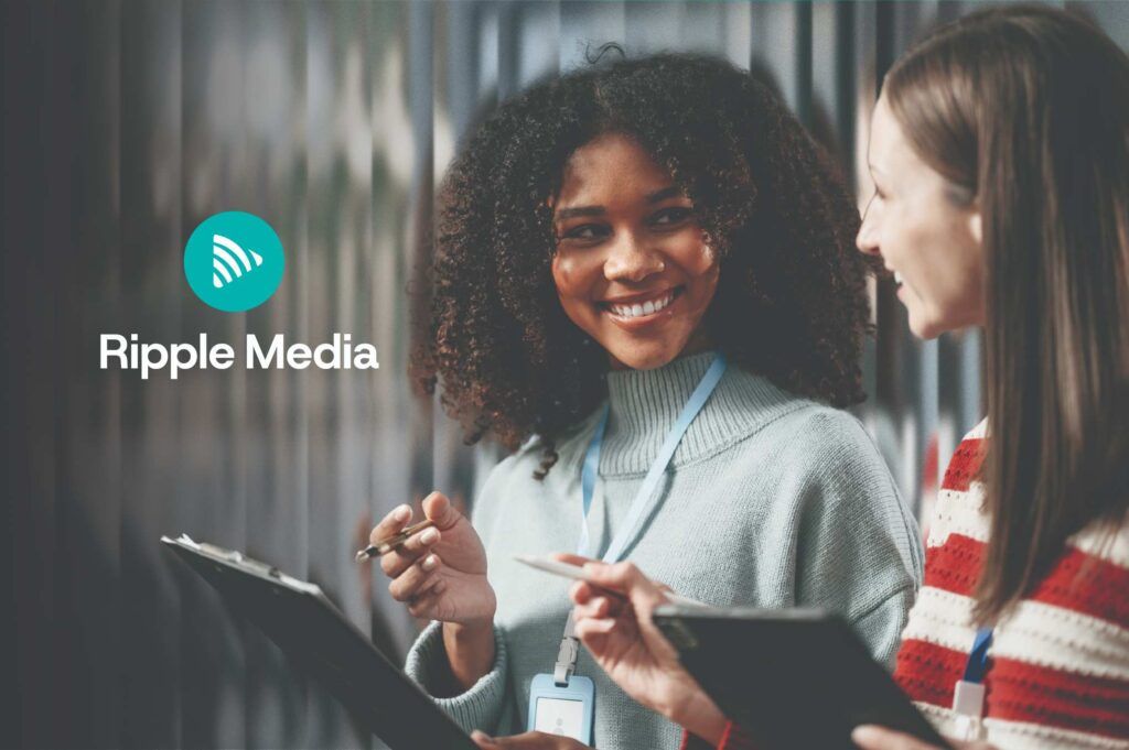 Ripple Media branded graphic featuring two smiling female team members in lanyards discussing work with clipboards, with the teal Ripple Media logo and name displayed clearly on the left side.