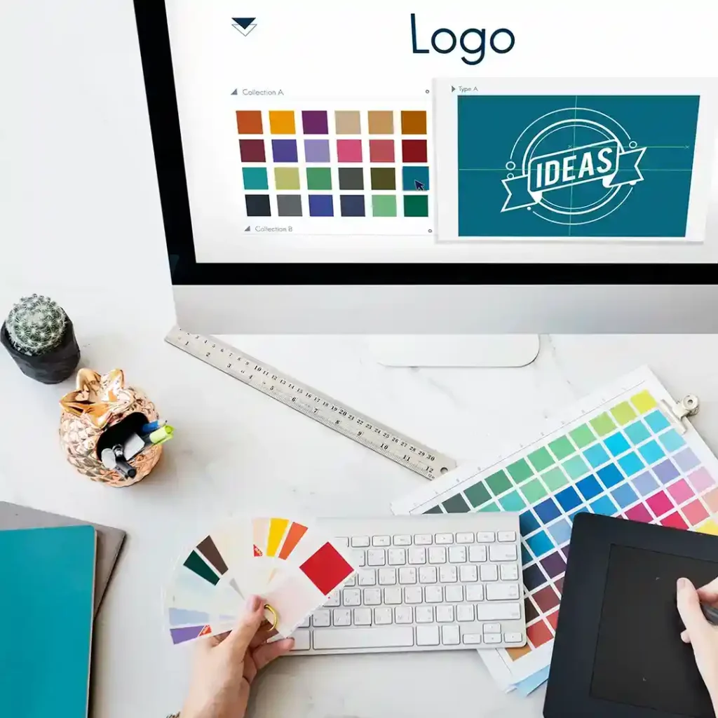 Designer reviewing logo drafts and color swatches on a workspace, preparing for a branding identity project