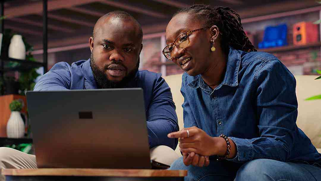 Two business partners reviewing content together on a laptop, collaborating on brand strategy and planning in a warm, modern workspace